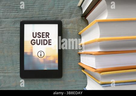 Guide de l'utilisateur document ouvert dans le dispositif e-book et livre différent sur la table en bois, vue de dessus Banque D'Images