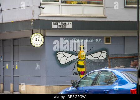Manchester, Royaume-Uni - 11.16 2024 : vue sur la rue avec les reflets de la tour Beetham et l'architecture et la signalisation uniques de Manchester. Symbole d'abeille Manchester Spraye Banque D'Images