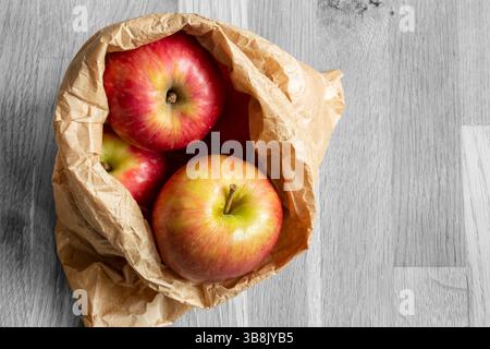 Pommes dans un sac en papier brun sur un fond de bois avec une couleur sélective. Concept d'emballage respectueux de l'environnement Banque D'Images