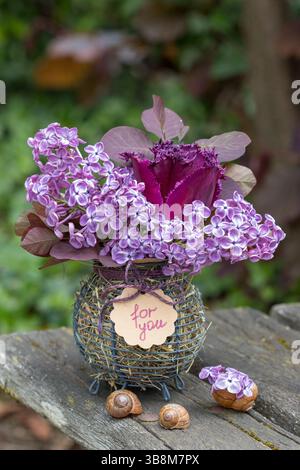 bouquet de tulipes violettes, fleurs de lilas et branches d'arbre à fumée dans un panier Banque D'Images