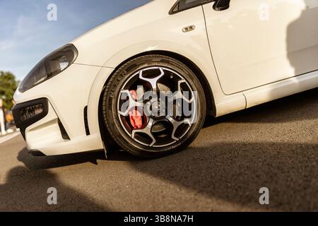 Rome, italie 4 mai 2025 : gros plan d'une voiture de sport blanche garée sur asphalte, mettant en évidence sa jante en alliage, son étrier de frein rouge et son pneu à profil bas Banque D'Images