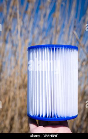 Cartouche filtrante de piscine de remplacement dans la main d'une femme. Traitement de l'eau, nettoyage de piscine, qualité de l'eau, concept. Réutilisation du filtre. Banque D'Images