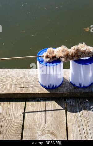 Заголовок photo conceptuelle pour la propreté de l'eau dans les systèmes naturels et humains. Queue séchée sur le dessus des cartouches filtrantes de rechange pour piscine. Banque D'Images