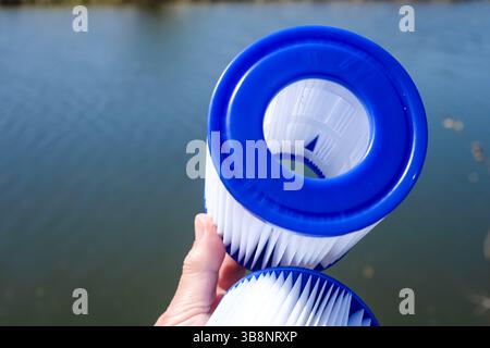 Cartouches filtrantes de piscine de remplacement dans la main d'une femme sur la toile de fond de l'eau. Traitement de l'eau, nettoyage de piscine, qualité de l'eau, concept. Réutilisation du filtre. Banque D'Images