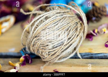 Gros rouleau de ficelle de jute brune pour l'artisanat couché sur une table en bois. Loisirs et thème des matériaux d'artisanat. Banque D'Images