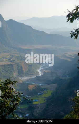 Une rivière traverse les collines du Népal, soutenant des villages et des fermes en terrasses. L'eau donne vie à ce paysage accidenté. Banque D'Images