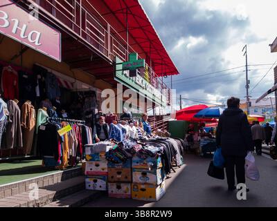 Kiev, Ukraine - 24 mars 2025. Les gens se promènent dans un marché de rue animé, parcourant les étals remplis de vêtements et de marchandises, profitant de l'atmosphère animée de la vie quotidienne en plein air. Banque D'Images