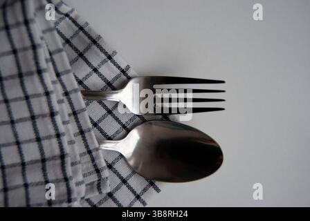 Heure du dîner. Une fourchette et une cuillère sur une serviette. Couverts isolés sur blanc. Banque D'Images