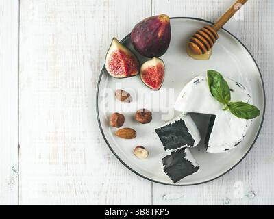 Fromage camembert noir inhabituel avec de la moisissure blanche.cuisine moderne à la mode, repas, nourriture.vue de dessus de l'assiette, tranches de camembert noir biologique, basi vert frais Banque D'Images