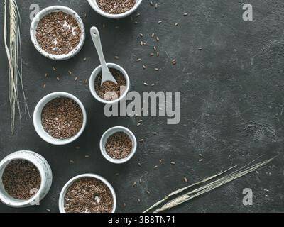 Graines de lin et épi de seigle sec sur fond sombre. Ensemble de petits bols avec graines de lin bio ou graines de lin. Les graines de lin sont riches en acides gras oméga-3. Copier Banque D'Images