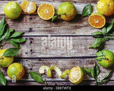 Mandarines vertes sur fond de bois ancien. Demi-mandarines fraîches et mûres, entières et pelées, avec feuilles, vue de dessus ou à plat. Copier l'espace pour le texte o Banque D'Images