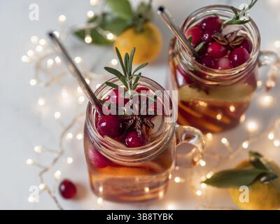 Sangria d'hiver dans des pots de maçon avec pailles en métal sur fond de vacances de noël. Tranches de fruits, canneberges et romarin décorés. Copier l'espace pour le texte ou Banque D'Images