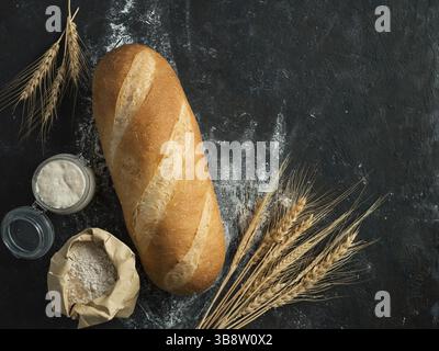 Pain de pain de Bomer blanc britannique ou de levain européen sur fond noir. Pain frais et pot en verre avec base de levain, avec fond en pape Banque D'Images