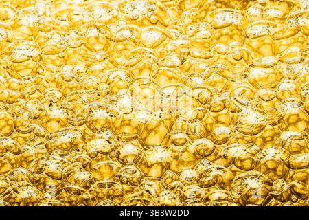 Gros plan de bulles jaunes. Fond abstrait de texture de mousse dorée. Surface de savon brillant avec des reflets. Macro shot de liquide de nettoyage. Banque D'Images