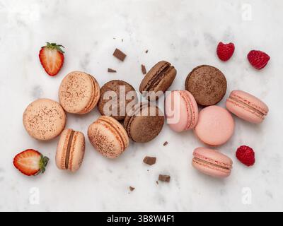 Composition avec macarons français sur fond de marbre blanc. Vue sur le dessus des macarons pastel colorés ou du macaron avec baies et chocolat Banque D'Images