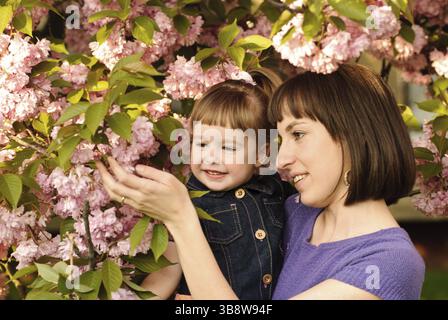 Mère et fille dans le jardin, sous l'arbre sakura. Ressort Banque D'Images