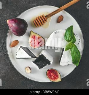 Fromage camembert noir inhabituel avec de la moisissure blanche.cuisine moderne à la mode, repas, nourriture.vue de dessus de l'assiette, tranches de camembert noir biologique, basi vert frais Banque D'Images