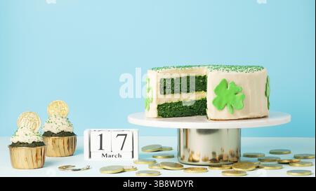 Concept de sucreries de la Saint Patrick. Gâteau de velours vert décoré de feuilles de shamrock vertes et de petits gâteaux aux pièces dorées pour la fête de la Saint Patrick Banque D'Images