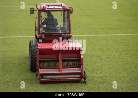 Un homme dans un tracteur avec un semoir à disques semant de l'herbe sur un terrain de football à Lubin, Pologne, Europe Banque D'Images