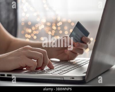 Cristmas shopping en ligne soncept. Gros plan les mains de la femme tenant la carte de crédit et en saisissant les informations de carte à l'aide du clavier d'ordinateur portable pour les achats en ligne Banque D'Images