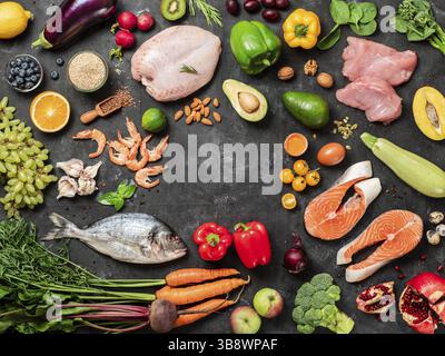 Pega Diet conept avec l'espace de copie au centre. Légumes et ingrédients alimentaires paleo - légumes, fruits, viande crue et poisson sur fond sombre. Haut vi Banque D'Images