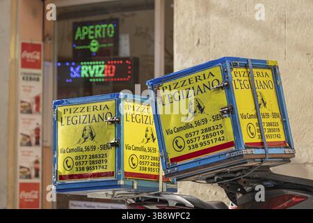 Boîtes de livraison de pizzas de couleurs vives devant un magasin avec une enseigne lumineuse au néon, image symbolique, Sienne, Toscane, Italie, Europe Banque D'Images