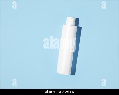 Vider la maquette de bouteille en plastique blanc par forte lumière. Vue de dessus ou plan de travail. Flacon opaque vierge sans emballage sur fond bleu. Maquette pour le package d Banque D'Images
