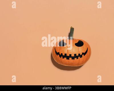 Citrouille d'Halloween sur fond orange. Concept d'Halloween avec espace de copie pour le texte ou la conception. Lumière dure. Jack-o-lanterne riant visage sur orang brillant Banque D'Images