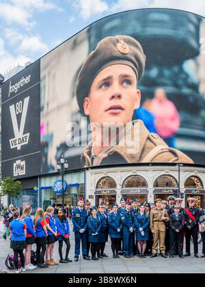 Londres, Royaume-Uni. 8 mai 2025. Mervyn Kersh, vétéran de la seconde Guerre mondiale, âgé de 100 ans (soutenu par des cadets, dont des membres de la brigade juive des filles et Harri J Douglas, l'acteur qui a joué le soldat), qui figure dans le film, et qui a participé au débarquement en Normandie et plus tard assisté à la libération du camp de concentration Bergen-Belsen - hommage au film VE80 pour VE Day à Piccadilly Circus à 15 heures, le moment où Churchill a déclaré la paix en Europe il y a 80 ans. Le film a été produit par Ocean Outdoor, The Together Coalition et M C Saatchi pour être projeté sur Piccadilly Lights. Crédit : Guy Banque D'Images