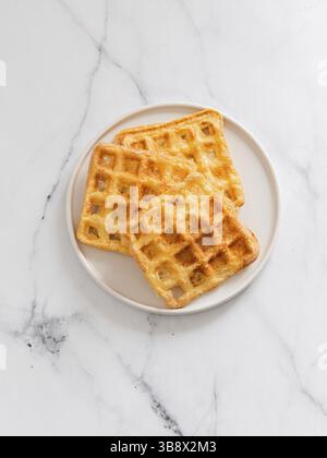 Gaufres à keto délicieuses parfaites. Deux ingrédients s'affle sur une plaque sur fond de marbre blanc. Œufs et gaufres au parmesan. Vue de dessus ou fl Banque D'Images