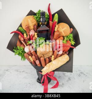 La viande et chese bouquet pour l'homme. Manger bouquet sur fond gris. Saucisses, légumes, fromage, pain et bouteille d'alcool fort en bouquet. G inhabituel Banque D'Images