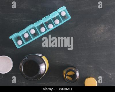 Vue de dessus de sept jour comprimé fort avec des pilules. Comprimé vert-box en bois sombre sur le tableau. Ouvrez la boîte de pilules et d'ouvrir les boîtes avec des pilules ou des vitamines. Copier l'espace. Haut Banque D'Images