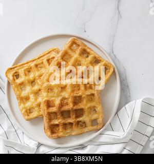 Gaufres à keto délicieuses parfaites. Deux ingrédients s'affle sur une plaque sur fond de marbre blanc. Œufs et gaufres au parmesan. Vue de dessus ou fl Banque D'Images