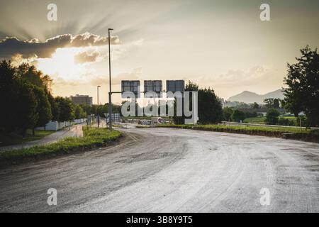 Panneaux de signalisation au loin avec rayons du soleil brisant à travers les nuages sur le chantier de construction de l'autoroute Banque D'Images