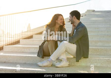Jeune couple profitant d'un moment romantique sur des marches ensoleillées. Style de vie. Vacances. Banque D'Images