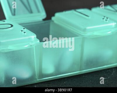 Extreme close up de sept jour comprimé fort avec des pilules. Comprimé vert-box avec mardi comprimés visible. Ouvrez la boîte de pilules sur fond noir Banque D'Images