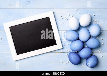 Concept de Pâques. Oeufs ombré dans des couleurs bleues sur fond en bois bleu avec tableau noir vide. Vue de dessus ou pose à plat. Couleurs bleues classiques à Pâques 20 Banque D'Images