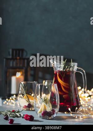 Sangria d'hiver sur fond sombre de noël. Jugful de sangria et verres avec tranche de fruits, canneberge et romarin. Copier l'espace pour le texte ou de Banque D'Images