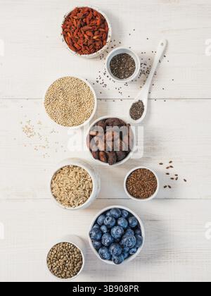 Divers superaliments en petit bol sur table en bois blanc.sélection super nourriture.Superfood comme bleuet, chia, cacao cru, goji, graines de chanvre, quinoa, br Banque D'Images
