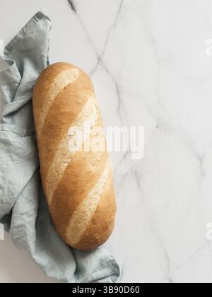 Pain British White Bloomer ou pain de pain européen Baton sur fond de marbre blanc. Vue de dessus ou pose à plat. Copier l'espace pour le texte ou la conception. Vertical Banque D'Images