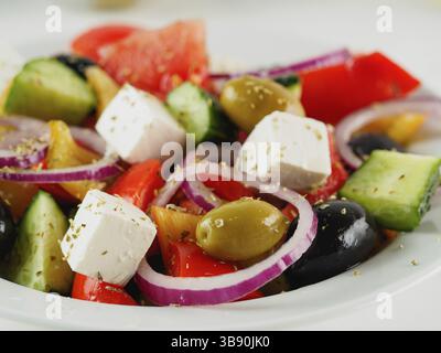 Salade grecque sur la table blanche, verticale. Salade grecque fraîche sur l'assiette. Voyant de touche haut. Gros plan. Mise au point sélective. Vue latérale Banque D'Images