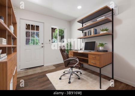 Un bureau à domicile confortable avec un bureau, une chaise, un ordinateur et des étagères Banque D'Images