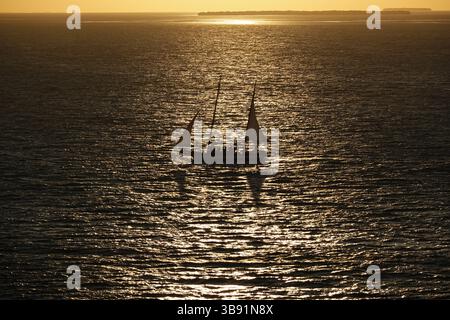 Une silhouette d'un voilier seul sur l'eau pendant le coucher du soleil. Banque D'Images