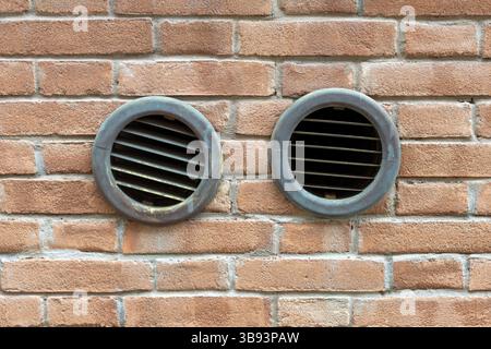 Deux grilles d'aération rondes dans le mur de briques Banque D'Images