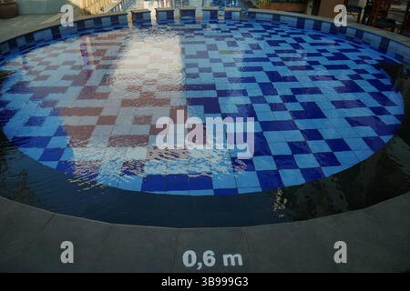 Piscine avec design circulaire et tuiles bleues apaisantes. Banque D'Images