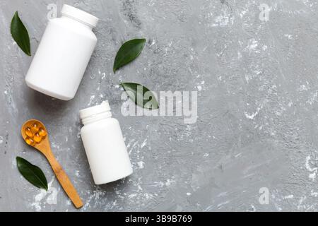 Les capsules Omega-3 se trouvent dans une bouteille blanche sur une table avec un fond de feuilles vertes. Comprimés d'huile de poisson. Additifs biologiquement actifs. omega 6, omega 9, vitam Banque D'Images