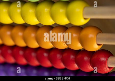 perles en bois colorées sur boulier pour le jeu des enfants, boulier pour enfants en bois pour l'apprentissage et le développement, perles rouges violettes et oranges en gros plan, côté Banque D'Images