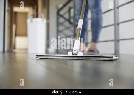 Femme nettoyant, essuyant le plancher de bois franc élégant dans un cadre moderne de maison. La femme au foyer utilise la vadrouille de nettoyage dans le salon confortable de la maison. Entretien ménager, travaux ménagers. Assainissement, propreté, hygiène, nettoyage, entretien Banque D'Images