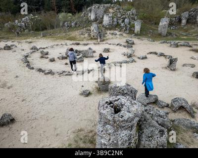 Mère et deux enfants explorent un terrain rocheux dans un paysage sec et semi-désertique. Les enfants jouent sur des formations de pierre pendant que la mère regarde, enjo Banque D'Images