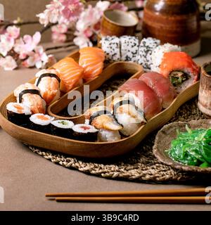 Ensemble de petits pains à sushis. Des petits pains à sushis japonais traditionnels avec du saumon frais, du thon, de l'anguille et des crevettes sur du riz. Servir sur une assiette en bois avec sauce soja, wakame sa Banque D'Images